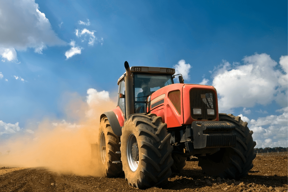 4 a large yellow tractor with four large wheels, driving through a muddy field